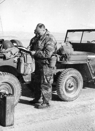 Un lieutenant porte sur le carnet de bord de sa jeep le complètement du plein d' essence qu'il vient de réaliser .